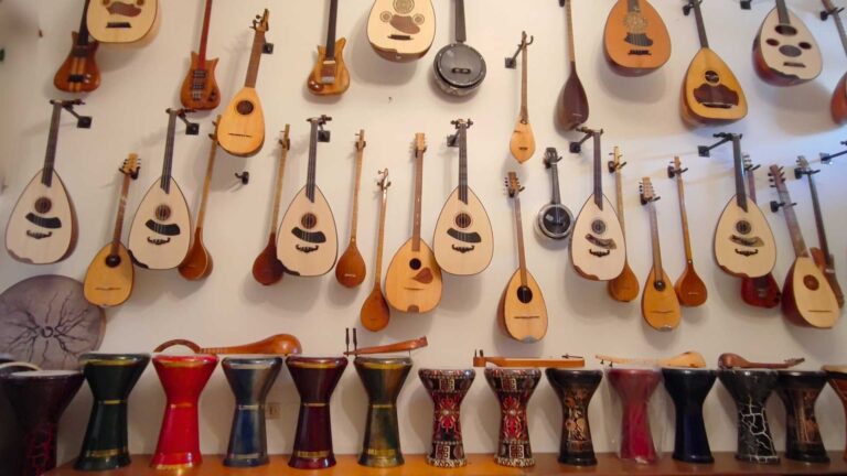 A variety of string instruments and colorful drums displayed on a wall and table.
